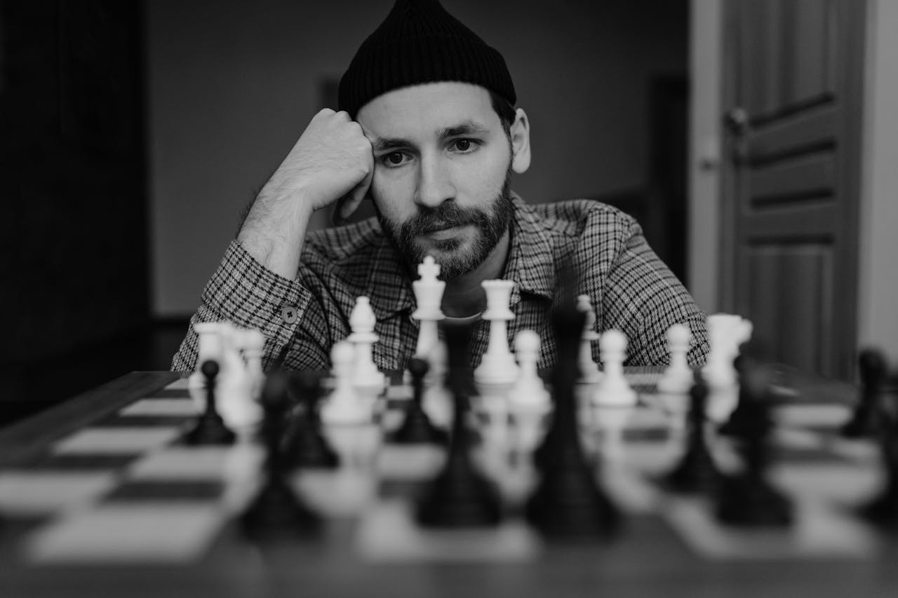 Black and white image of a thoughtful man playing chess, focusing on strategy.