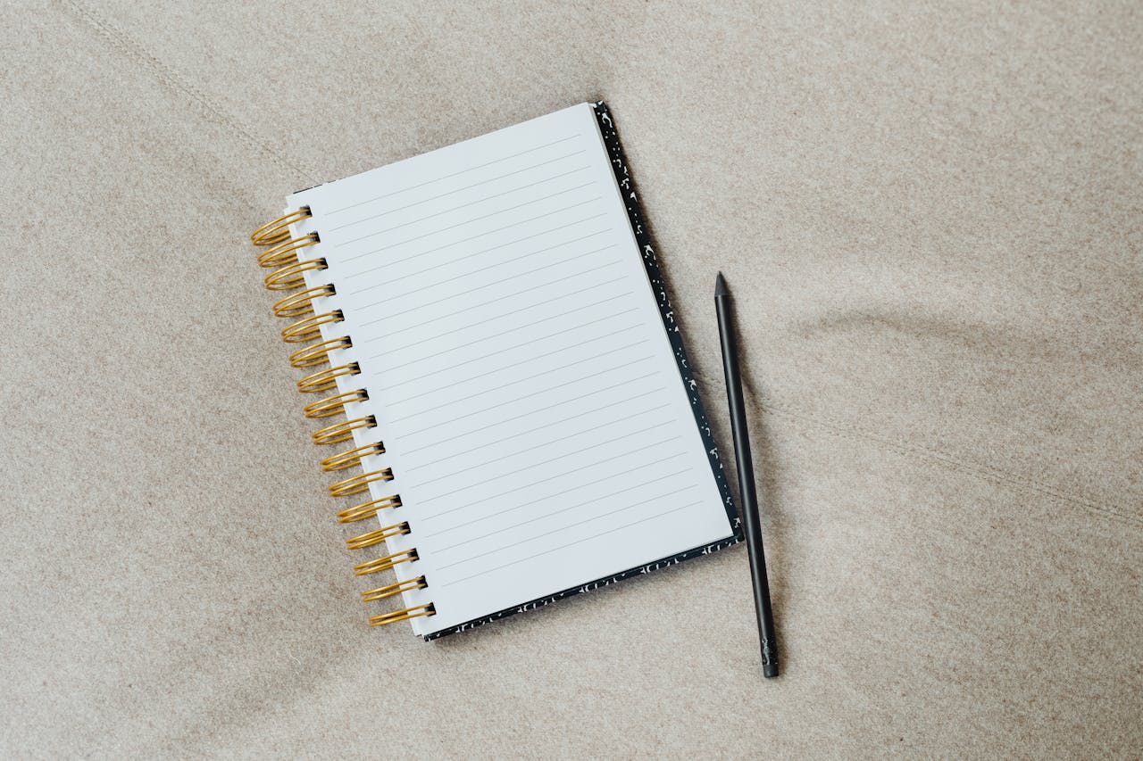 A minimalist notebook with a pencil on fabric surface, ideal for writing themes.