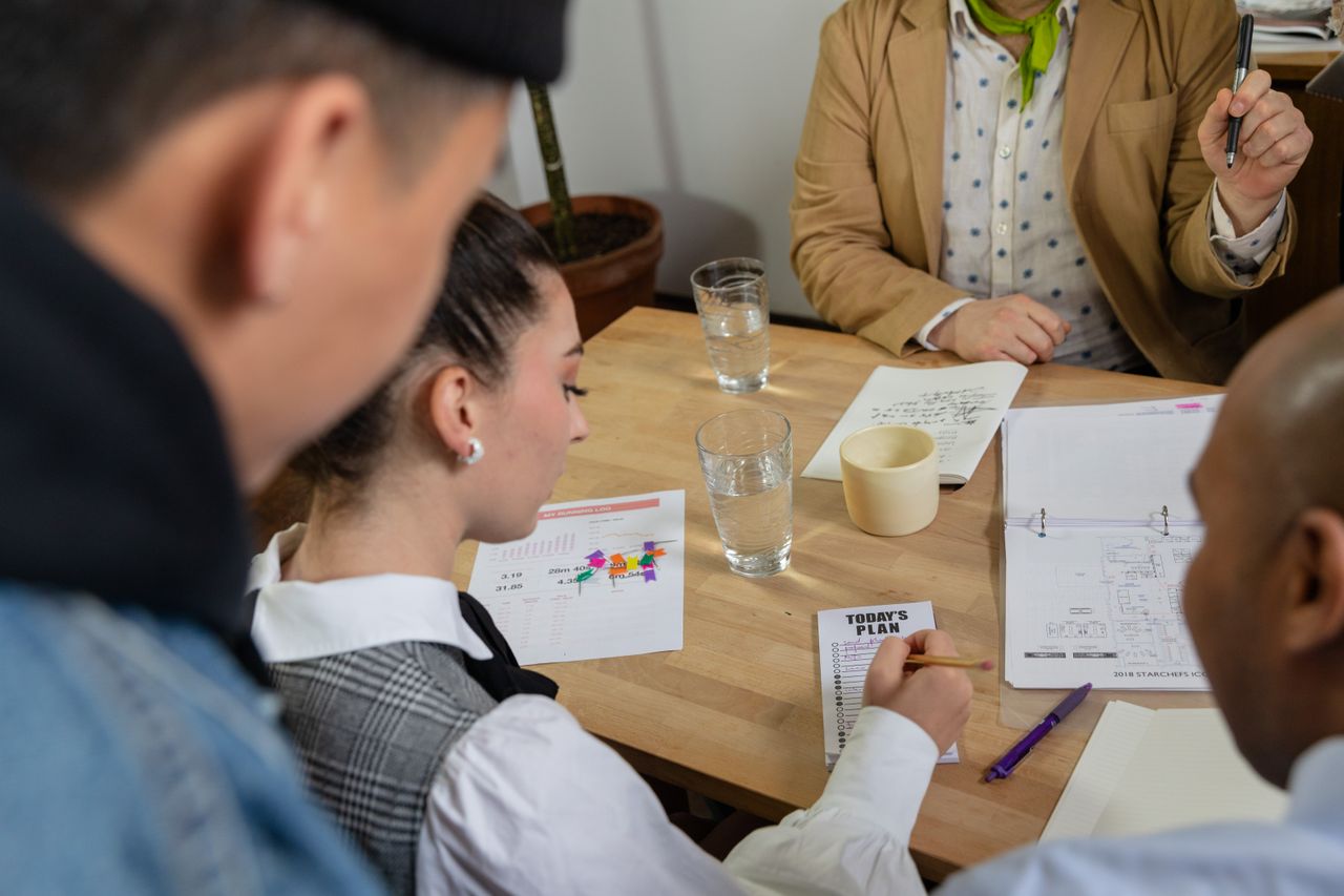Diverse team engaging in a strategic meeting, reviewing plans and documents at a table.